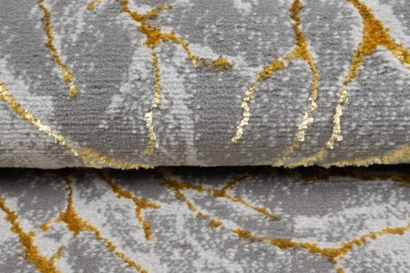 Jednoduchý moderní koberec v šedé barvě se zlatým motivem