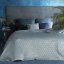 Cuvertură de pat matlasată din velur pe un pat albastru deschis